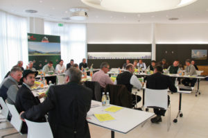 Menschen an Tischen in einem Konferenzsaal