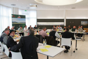 Menschen an Tischen in einem Konferenzsaal