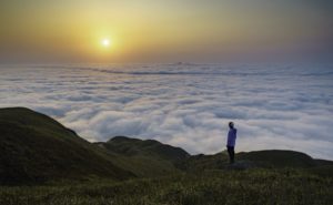 Mann auf einem Gipfel über einem Wolkenmeer