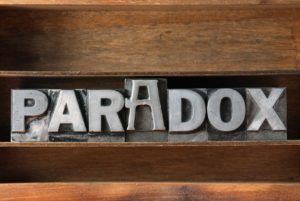 das Wort Paradox in Metallbuchstaben auf einem Regal