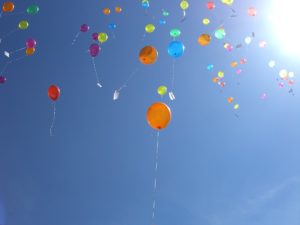 heliumgefüllte Ballons steigen in einen blauen Himmel
