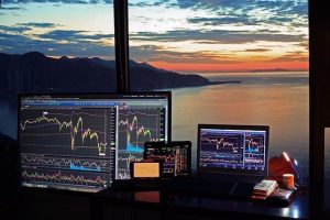 Laptops mit Aktienkursen vor Ausblick auf einen Sonnenaufgang