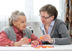 Eine Betreuerin puzzelt mit einer älteren Dame