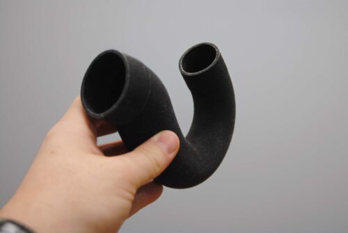 Bauteil in schwarz wird von einer Hand gehalten