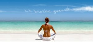 Frau im Schneidersitz von hinten vor traumhafter Meerkulisse