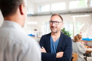 Mann mit verschränkten Armen lächelt einen möglichen Bewerber an