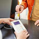 Hand führt KK-Karte in das Lesegerät