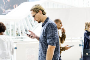 blonder Mann schaut auf sein Handy