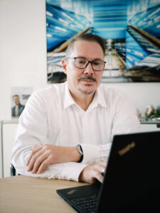 Mann vor einem Laptop schaut skeptisch