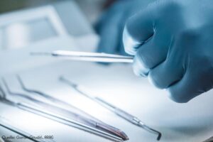 Hände in Gummihandschuhen halten medizinisches Werkzeug