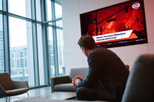 Mensch im Wartezimmer sitzt seitlich zu einem TV